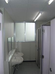 女子トイレ内部の写真。右側にトイレブース、左側に洗面器があります。洗面器の水栓は自動水栓となっています。