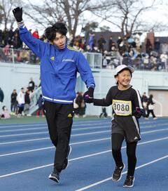 ロジスティード陸上部選手と女子児童が手を繋ぎ入場する写真