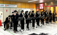 駅前で吹奏楽部がクリスマスコンサートを行う画像
