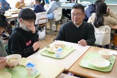 副総支部長が食べる生徒を見守っている