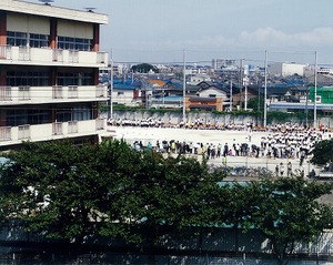 校庭に大勢の学生たちがいる写真