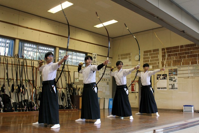 弓道場で弓を構える4人