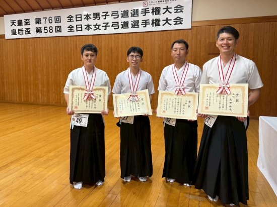 メダルと表彰状を持つ貝谷さんと他の入賞者