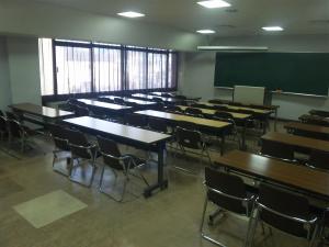 202会議室入り口からの様子です。3人がけテーブルが3列並んでいます。黒板とスクリーンも備え付けてあります。